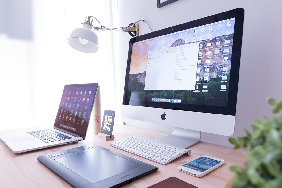 Computer, laptop, a phone and other tech on a desk