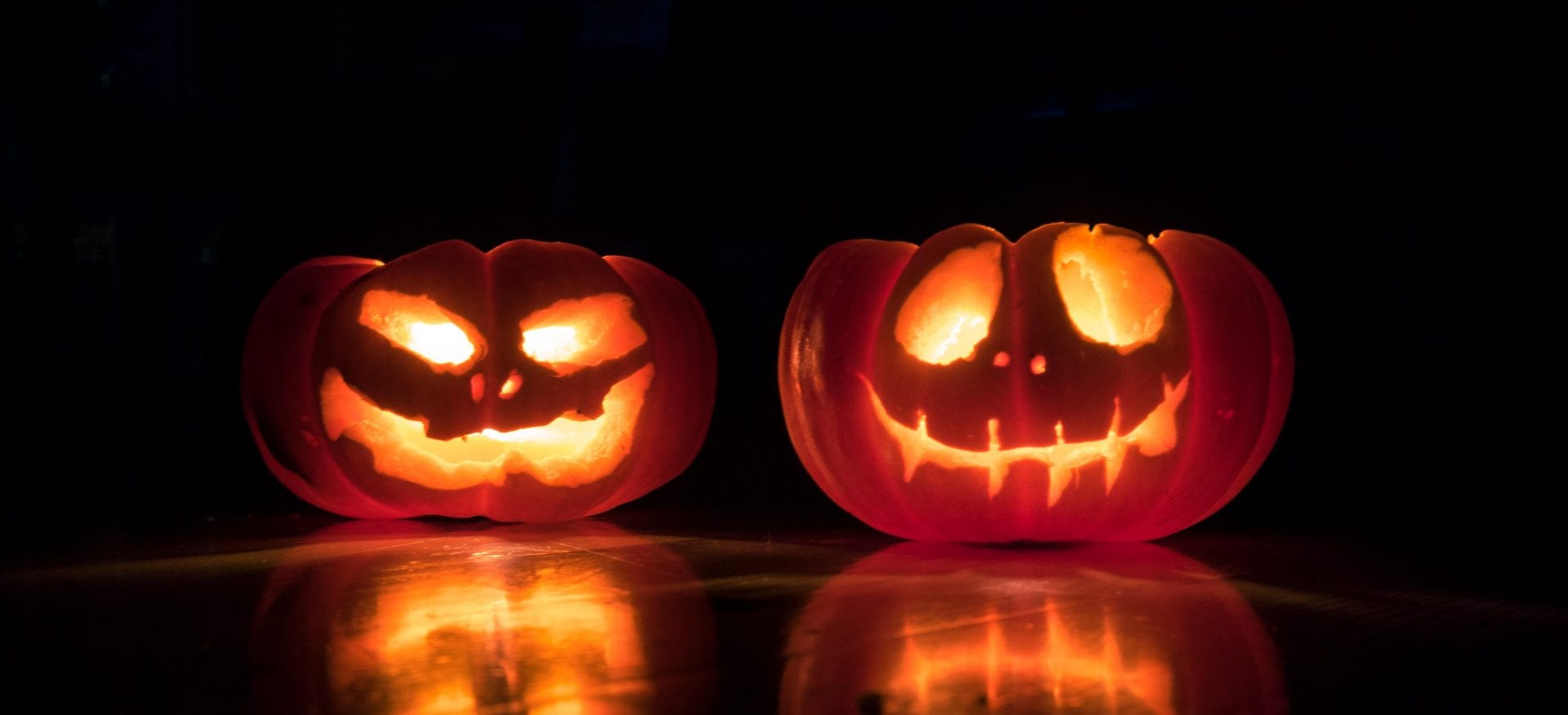 Two carved pumpkins with candlelight inside