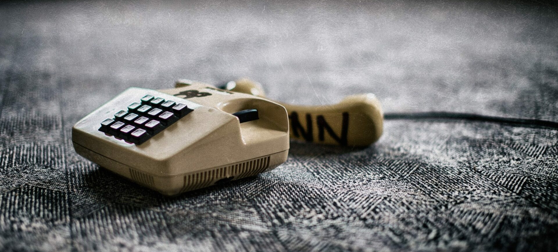 An old white landline phone on a grey floor